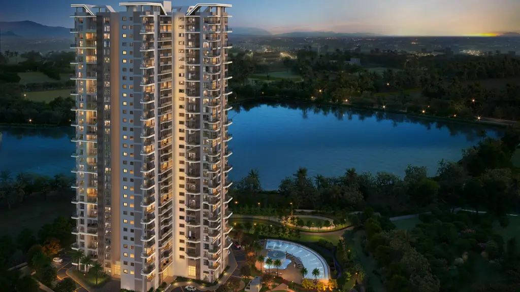 Aerial view at dusk of The Solitaire tower, its windows lit, above the lake and the trees