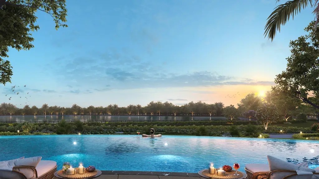 An infinity pool at sunset running out towards the lake and the trees on its far shore