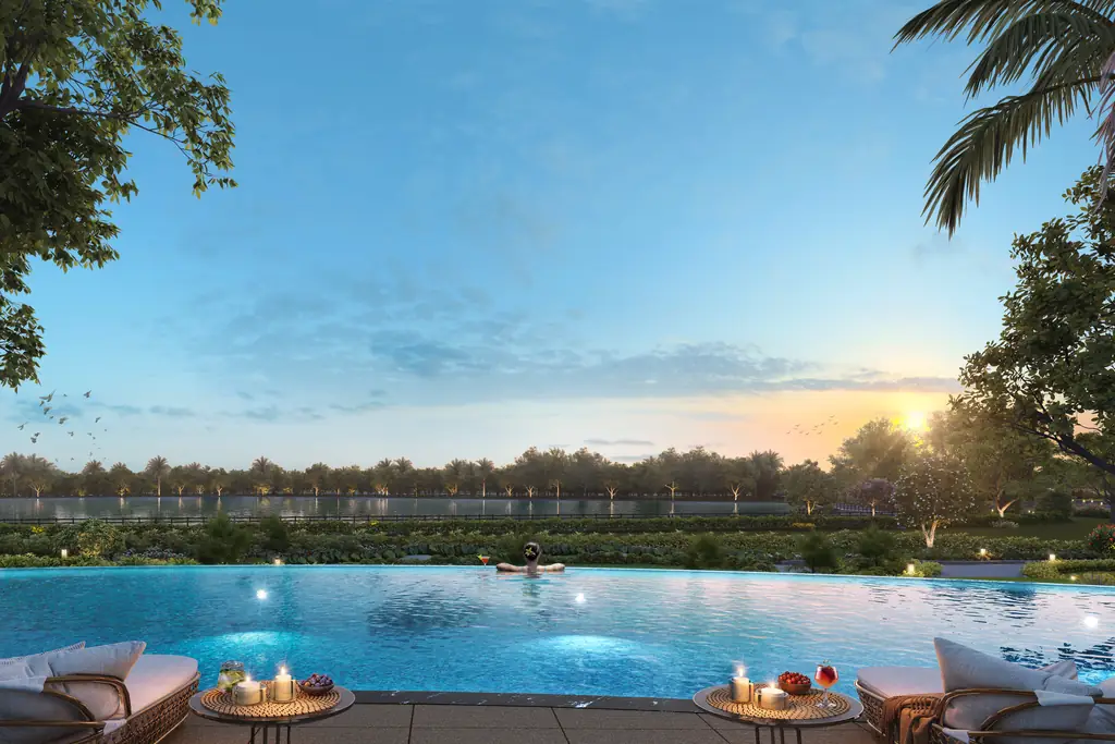 An infinity pool at sunset running out towards the lake and the trees on its far shore